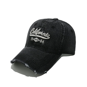Detailed macro of vintage washed denim cap with California embroidery and distressed brim