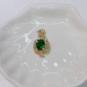 Detailed macro shot of golden sunburst pendant with green oval stone on shell tray