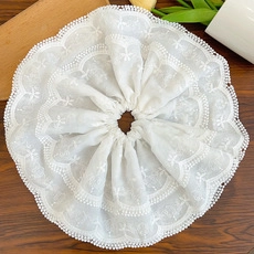 Detailed macro view of white lace scrunchie with intricate embroidery and beaded edges