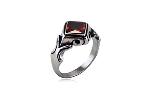 Macro shot of silver gothic ring with a square red gemstone and vintage floral patterns