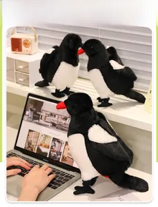 Detail of three plush magpie dolls with red beaks on a desk, showing soft texture