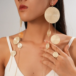 Close-up of long gold tiered disc tassel earrings worn by a model to show texture