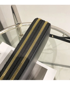 Detail shot of the durable double golden metal zippers on the black leather clutch bag
