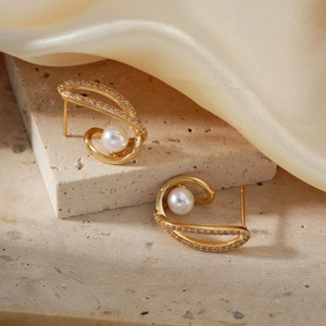 Vue détaillée des boucles d'oreilles perles dorées et zircon sur pierre et tissu en soie