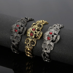 Macro view of retro skull bracelets in gold, silver, and black with red gemstone eyes
