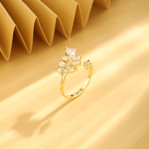 Gold leaf open ring with zircon inlay and elegant shadow detail on warm background