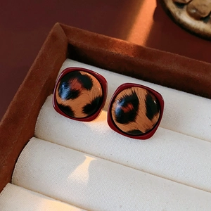 Gros plan de boucles d'oreilles carrées léopard avec cadre rouge dans un écrin de luxe