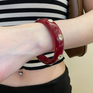 Macro shot of deep red acrylic bangle with gold-set rhinestones in vintage style