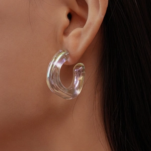 Close-up of iridescent C-shaped resin earrings with aurora finish on model