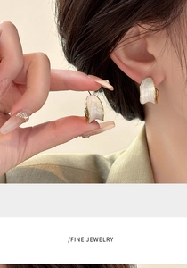 Macro detail of French vintage C-shape earrings with pearly enamel and 18K gold edges