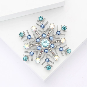 Broche flocon de neige argentée avec strass bleus sur blocs géométriques blancs