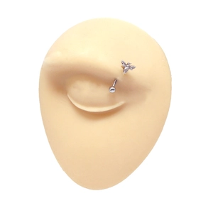 Detailed view of stainless steel bee eyebrow piercing on professional silicone model