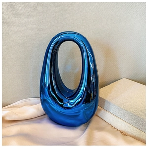 Close-up of blue electroplated ceramic handbag ornament on soft beige silk fabric