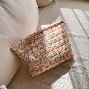Dettaglio della borsa da trucco trapuntata a fiori beige con etichetta in tessuto