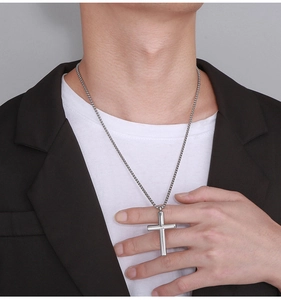Close-up of a silver stainless steel cross pendant necklace worn with a black blazer