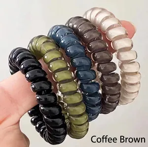 Detail of five durable spiral hair ties in neutral colors shown on a hand