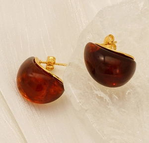 Macro shot of amber stud earrings with 18K gold base on elegant silk fabric