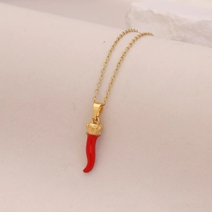 Detail of a gold necklace featuring a red chili pendant with a small crown cap