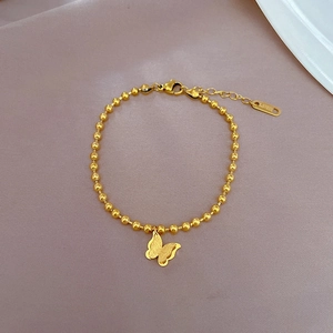 Detail of titanium steel gold beaded bracelet featuring a delicate butterfly charm