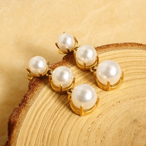 Elegant gold drop earrings with triple white pearls on natural wood display