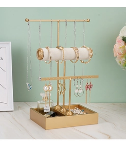 Detail of 3-tier gold metal jewelry stand featuring gray velvet rolls and earring organizer
