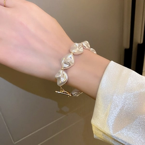 Détail du bracelet en perles irrégulières avec fermoir en T doré porté au poignet
