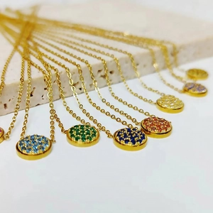 Macro view of gold stainless steel necklaces with colorful pavé rhinestone disc pendants