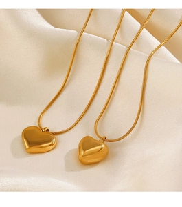 Close-up of dual 18K gold plated heart pendants on elegant snake chains over silk