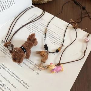 Detail view of plush puppy and cartoon cat pendants with wooden beads on an open book