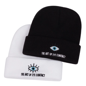 Détail de la broderie 'The Art of Eye Contact' sur les bonnets en maille noirs et blancs