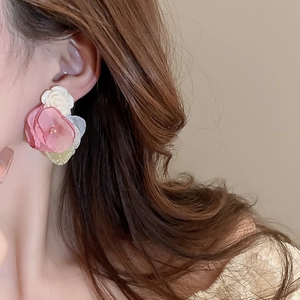 Close-up of elegant floral earrings with pink lace petals and white roses on model