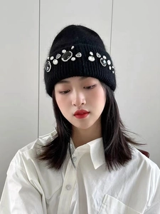Detailed close-up of a black knit beanie with shimmering rhinestone embellishments