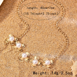 Elegant gold flower pearl necklace displayed on golden sand with a seashell accent
