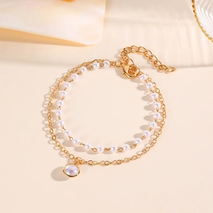 Detailed view of a dual-layer baroque pearl bracelet with gold chain and circular pendant