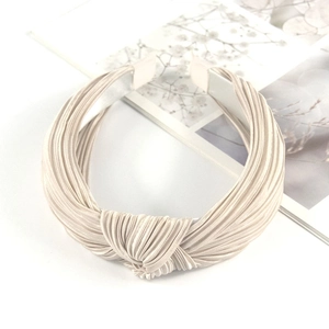 Detail of pleated champagne satin fabric headband with a stylish central knot design