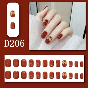 Detail of burgundy press-on nails with golden bows, glitter accents, and 24-piece set