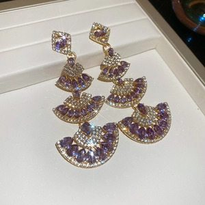 Macro shot of tiered purple teardrop earrings with gold-tone fan-shaped elements