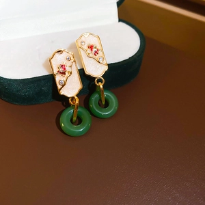 Detail of vintage Chinese style earrings with green jade-like stone and gold finish