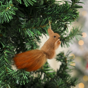 Close-up of a realistic squirrel ornament with plush fur hanging on a Christmas tree