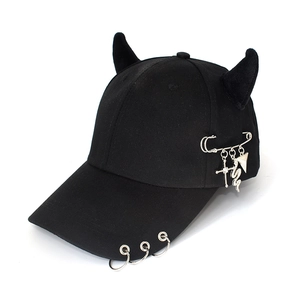 Detail view of black punk baseball cap with devil horns and silver metal cross pendants