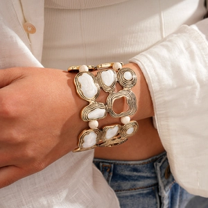 Detailed view of bohemian wide gold bracelet with marble textures and small white beads
