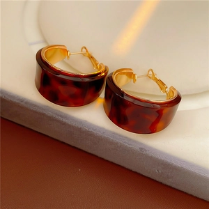 Detail von C-förmigen Schildpatt-Resin-Ohrringen mit goldener Metallumrandung