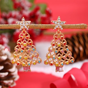 Macro view of Christmas tree earrings with colorful rhinestones on a wooden branch
