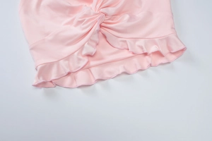 Detailed macro view of pink summer outfit showing knot design and ruffle hem details