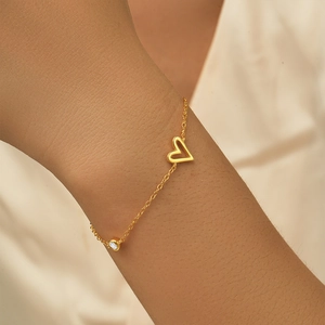 Close-up of a gold s925 silver heart bracelet with a sparkling round diamond on wrist