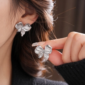 Macro view of matte silver flower stud earrings with central rhinestone for women