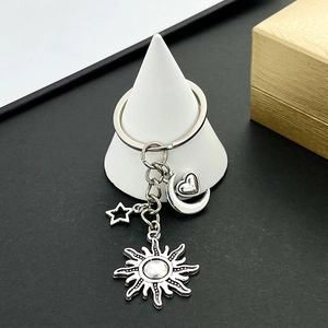 Detailed close-up of silver alloy sun moon star and heart pendants on a metal keychain