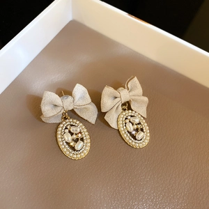 Detailed macro view of vintage bow earrings with pearls and rhinestones on a leather tray