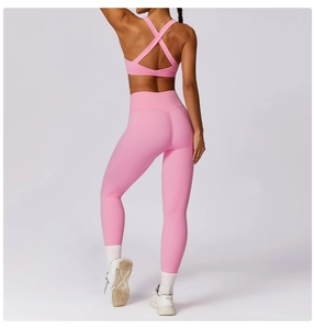 Close-up of pink high-waist yoga leggings and cross-back sports bra with seamless stitching