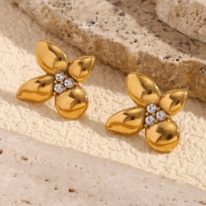 Polished 18K gold flower earrings with micro-set white diamonds on a stone background